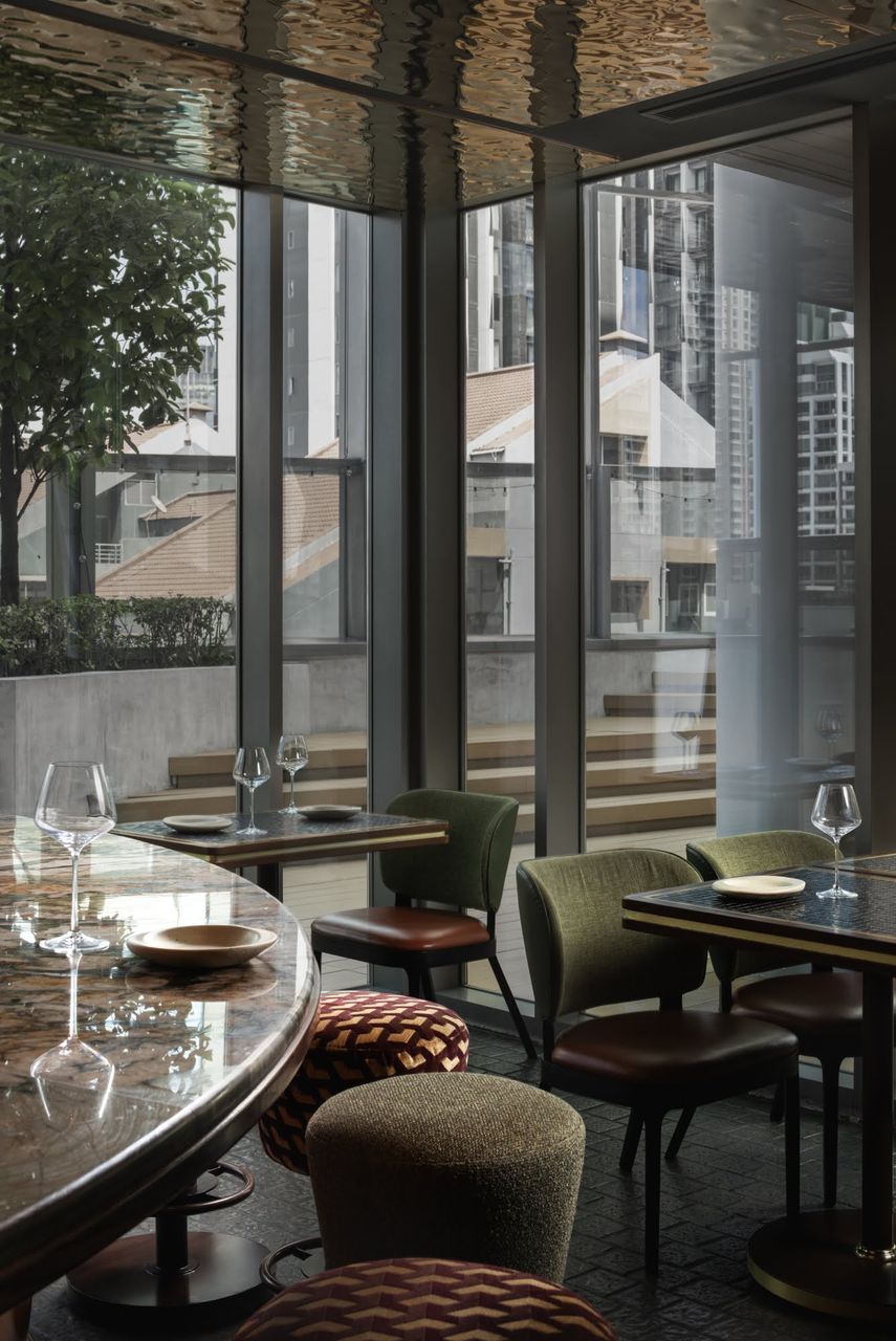 A window-side dining corner with laid tables, wine glasses and patterned tilework