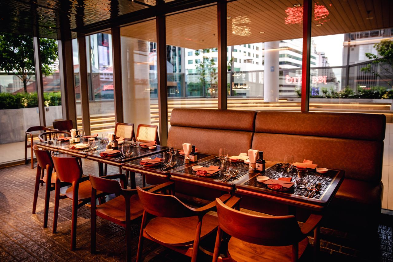 Window-bay seating in the dining room at dusk, tables laid for service