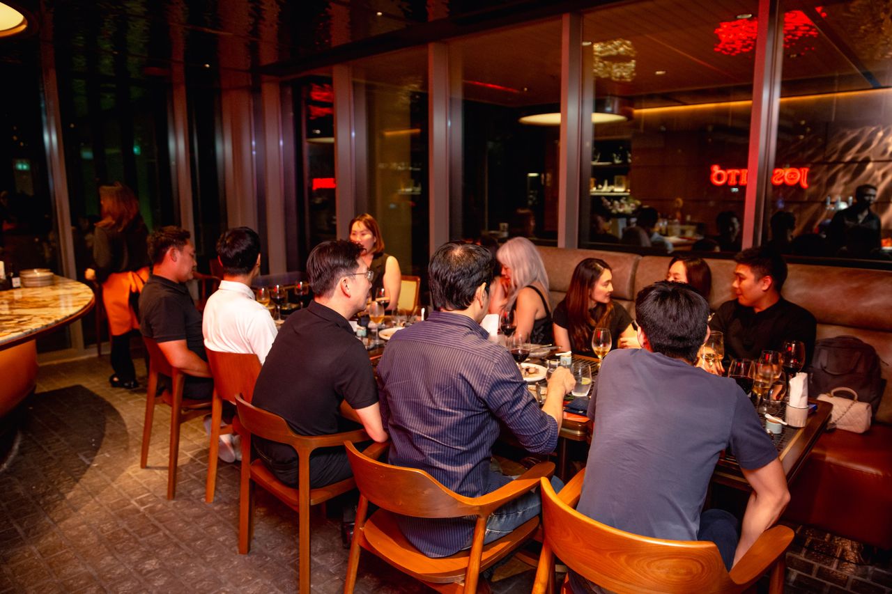 The dining room at night with a long table of guests mid-meal