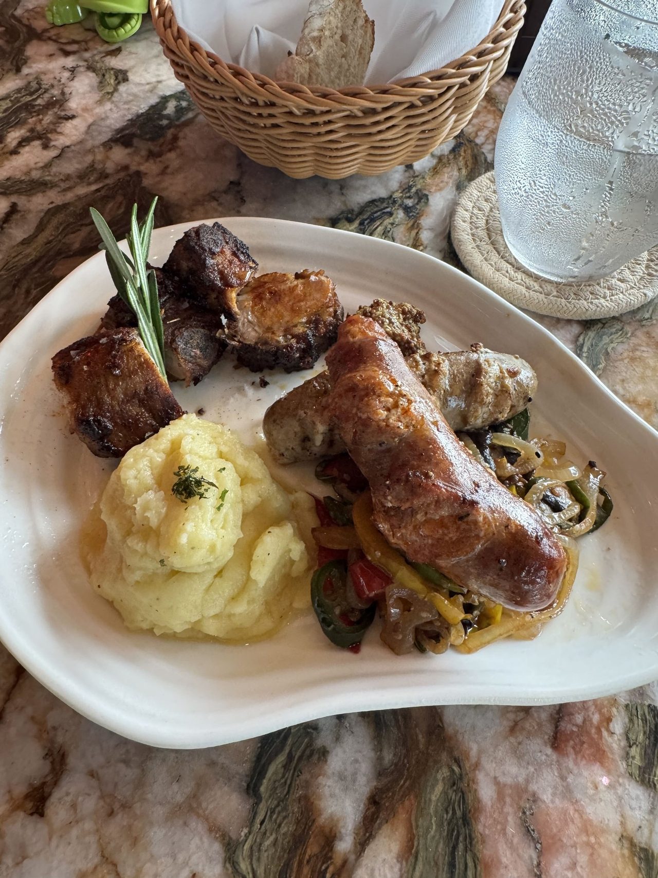 Grilled sausages and pork on sautéed peppers and onions, with potato purée, grain mustard and rosemary