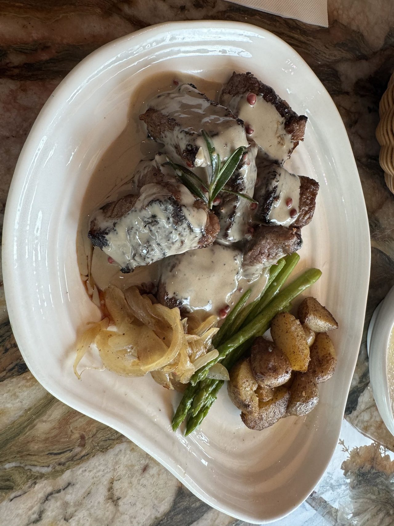 Grilled steak bites under a pink-peppercorn cream sauce with asparagus, onions and roast potatoes