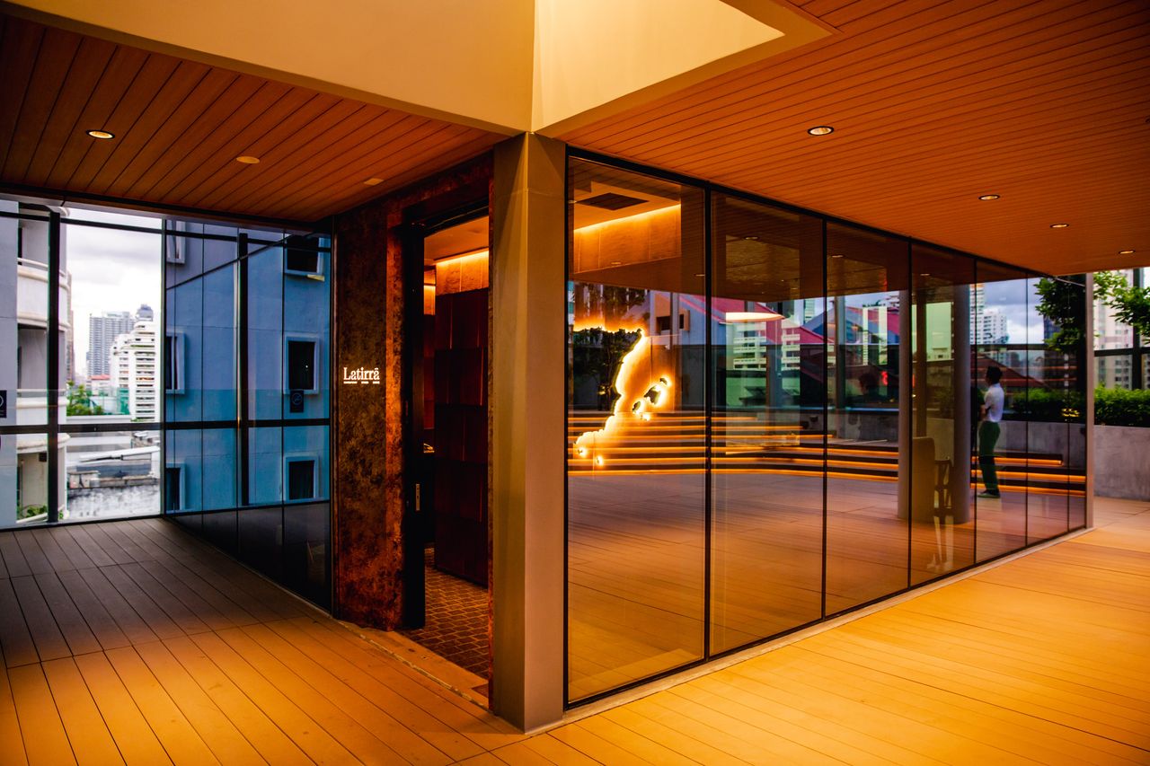 Latirra's glazed corner frontage seen from the timber terrace deck at dusk
