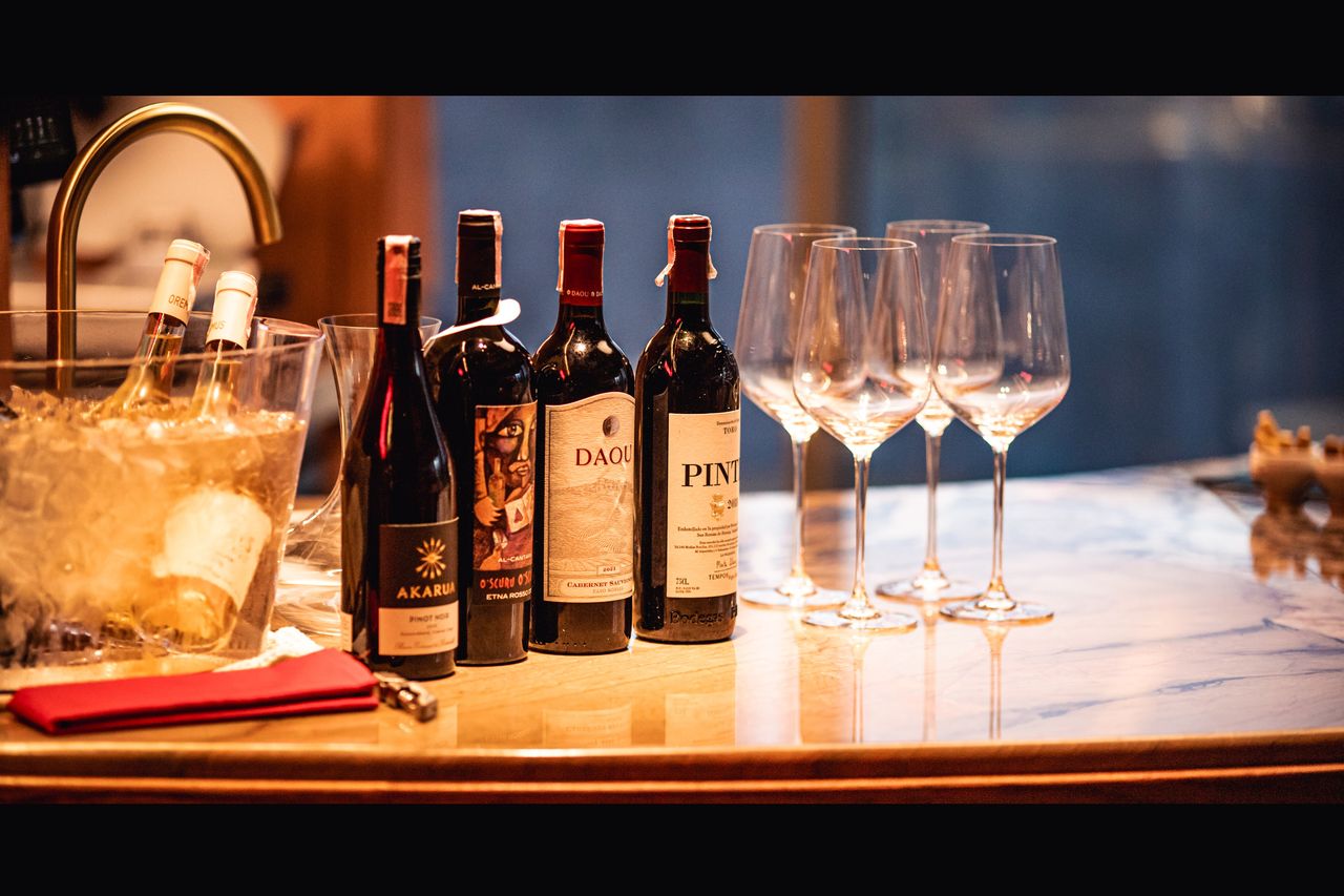 A row of Spanish wine bottles and stemmed glasses beside an ice bucket
